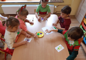 Dzieci stemplują palcami maczanymi w farbie obrazek wybranego owocu