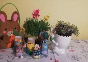 Dekoracje wielkanocne stojące na stole: zajączek pisanki, rzeżucha w doniczce