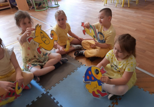 Dzieci ubrane na żółty trzymają sylwety kaczuszek