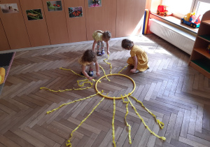 Dziewczynki układają promienie słońca z żółtych wstążek