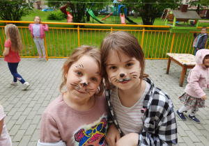 Dwie dziewczynki z pomalowanymi twarzami pozują do zdjęcia