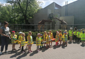 Dzieci stoją przy wybiegu dla żyraf