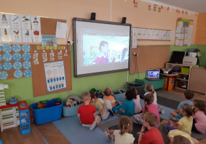 Dzieci oglądają kolegów ze szkoły na tablicy interaktywnej