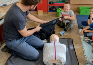 Chłopiec jest przyciągany do ratownika za pomocą bluzy - prezentacja sposobu pomocy osobie tonącej