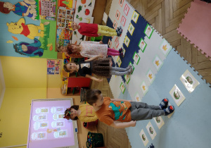 Dzieci uczestniczą w grze - stoją na ilustracjach warzyw