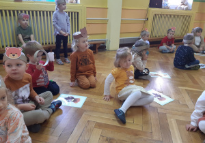 Dzieci siedzą przy ilustracjach z misiami