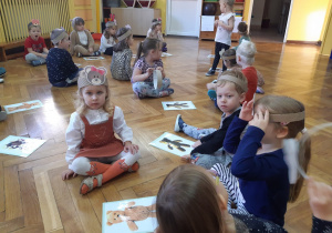 Dzieci siedzą przy ilustracjach z misiami