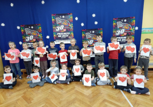 Dzieci pozują do zdjęcia trzymając wykonane przez siebie prace prace - wyklejane serca