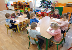Dzieci wykonują pracę plastyczną przy stolikach