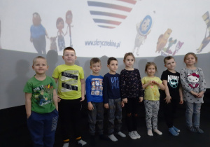 Dzieci pozują do zdjęcia przed ekranem kinowym