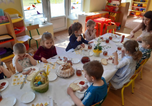 Dzieci jedzą wielkanocne śniadanko przy wspólnym stole