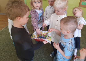 Chłopiec częstuje dzieci czekoladowymi jajeczkami