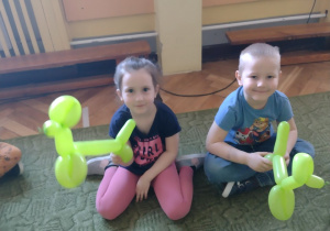 Dwoje dzieci trzyma w rękach pieski z balonów