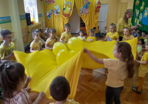 Dzieci podrzucają balony na kawałku materiału
