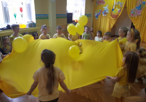 Dzieci podrzucają balony na kawałku materiału
