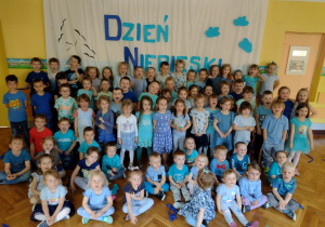 Dzieci pozują do zdjęcia na tle napisu "Dzień Niebieski"
