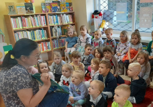 Dzieci patrzą na prezentowaną przez bibliotekarkę książeczkę