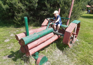 Chłopiec siedzi w drewnianym ciągniku