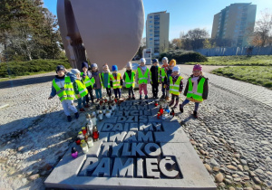 Dzieci stoją przy tablicy pamiątkowej