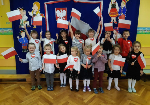 Dzieci z grupy trzeciej pozują do zdjęcia trzymając flagi Polski
