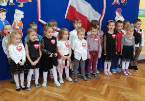 Dzieci śpiewają hymn Polski na tle dekoracji związanej z Narodowym Świętem Niepodległości