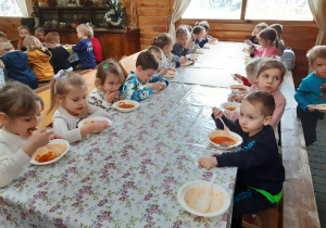 Dzieci jedzą zupę przy wspólnym stole