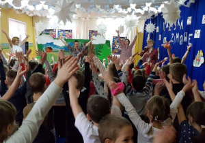 Dzieci i nauczyciele trzymają ręce uniesione w górę